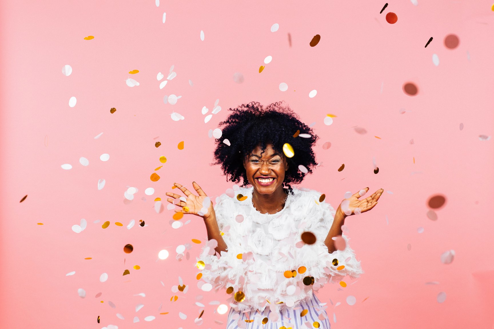 Celebrating happiness, young woman with big smile throwing confetti